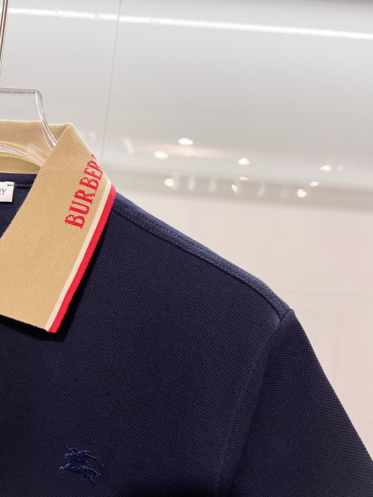 Dark blue Burberry polo shirt with small horse logo on sleeve and striped collar