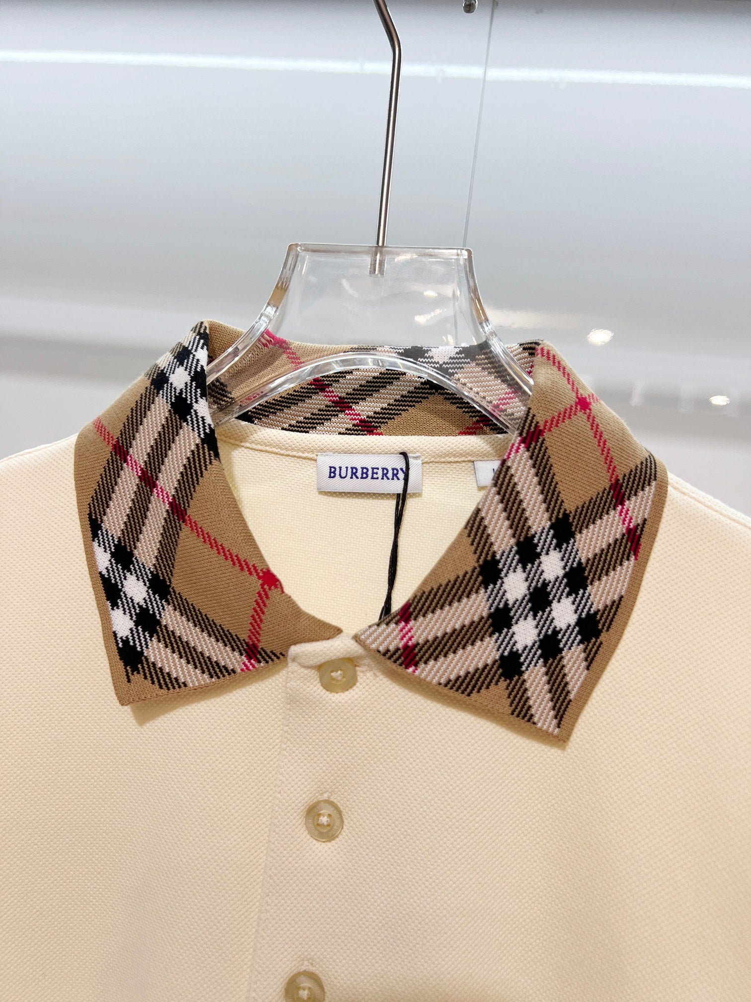 Cream polo shirt with check collar and gold button placket, close-up