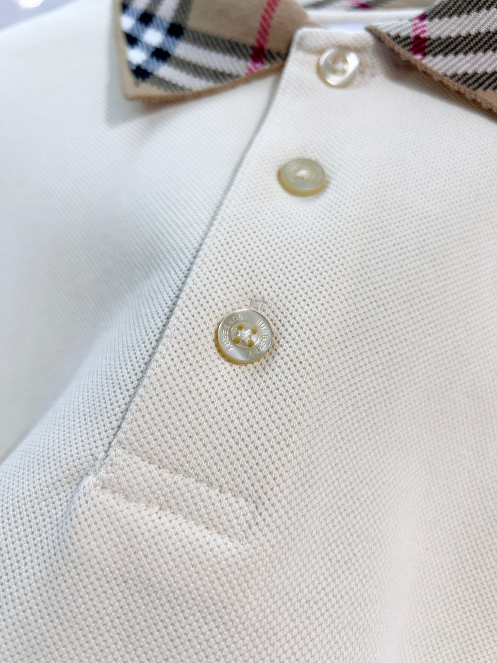 Cream polo shirt front with gold buttons and check collar corner