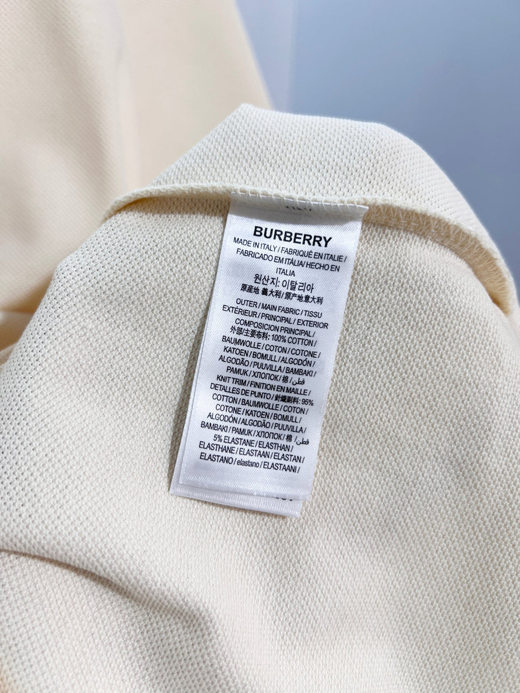 Cream polo shirt care label patch on inner collar seam