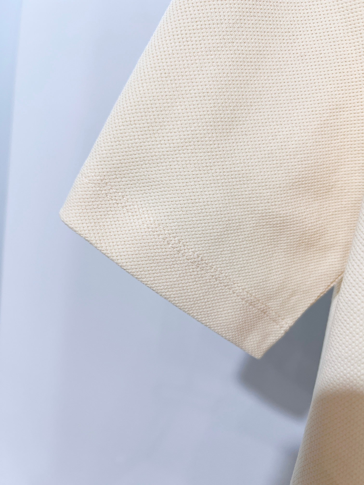 Cream short-sleeve polo shirt fabric close-up, collar edge visible
