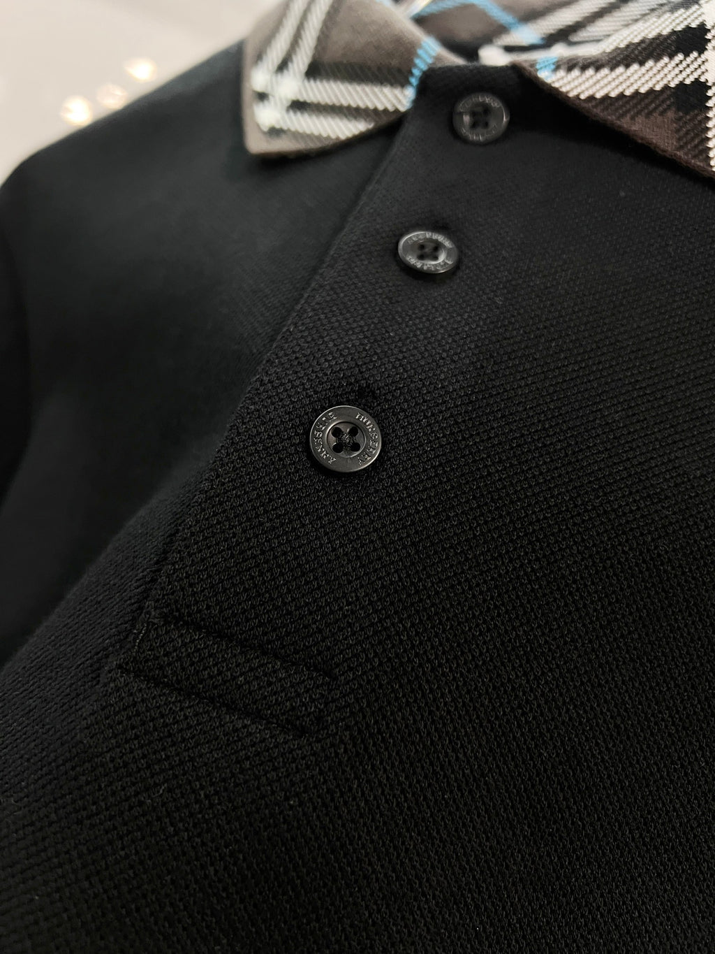 Black polo shirt front with three buttons and Burberry plaid collar