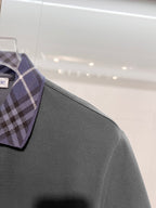 Mens short-sleeve polo shirt in dark gray on hanger with plaid collar edge