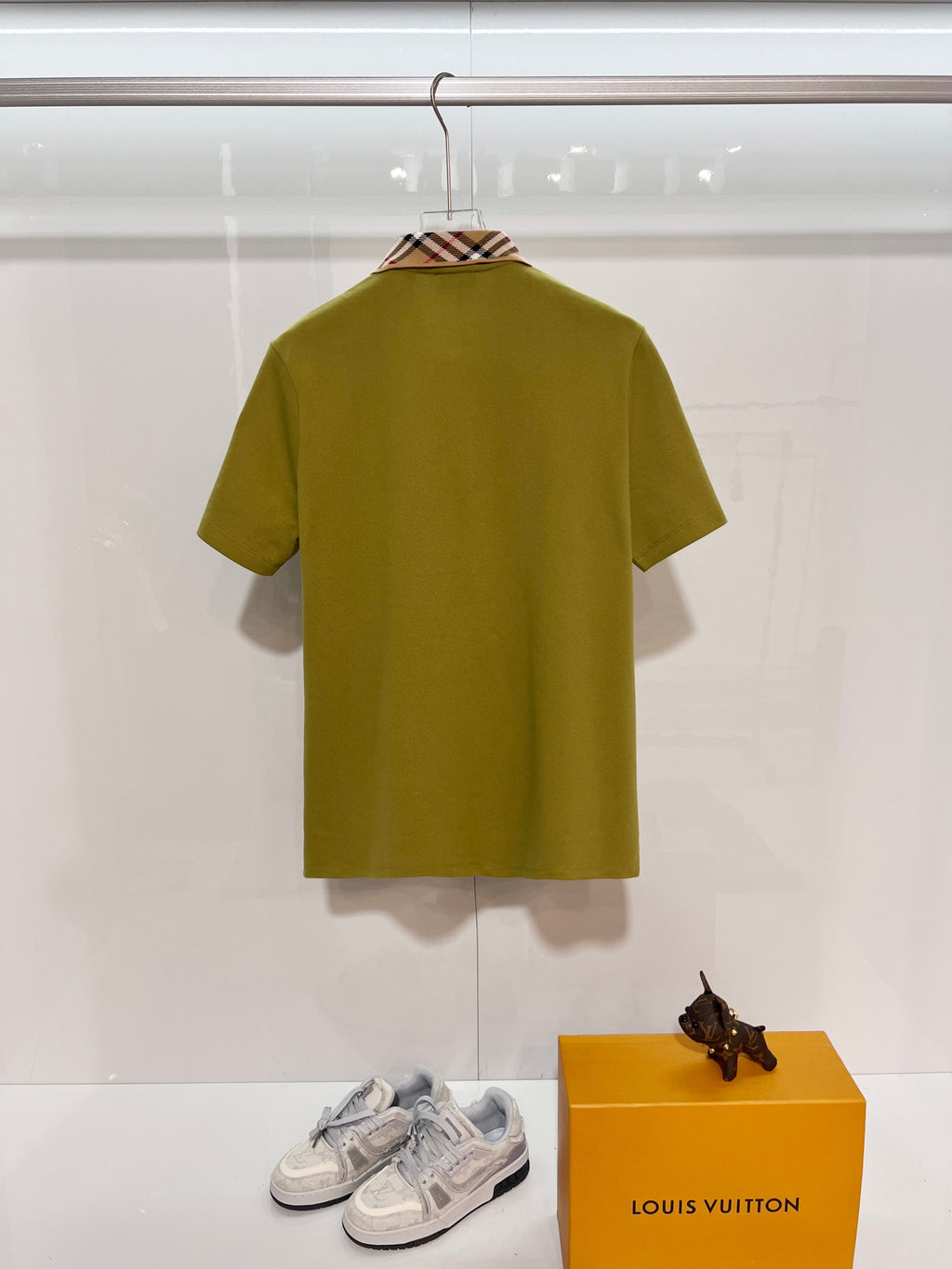 Olive green short-sleeve polo shirt on a hanger, back view