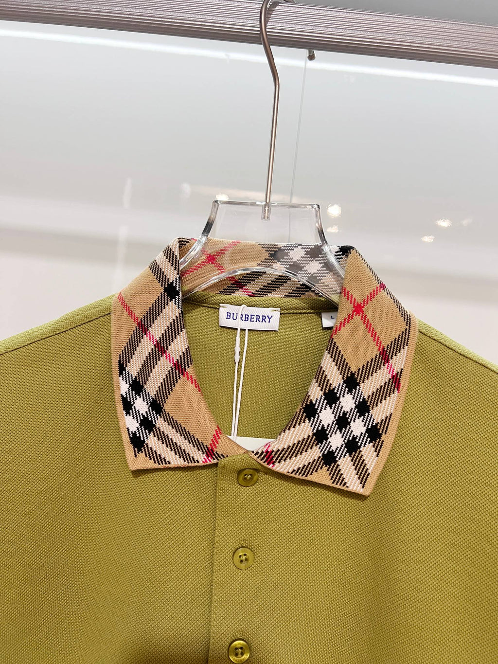 Olive green polo shirt with plaid check collar and button placket, close-up