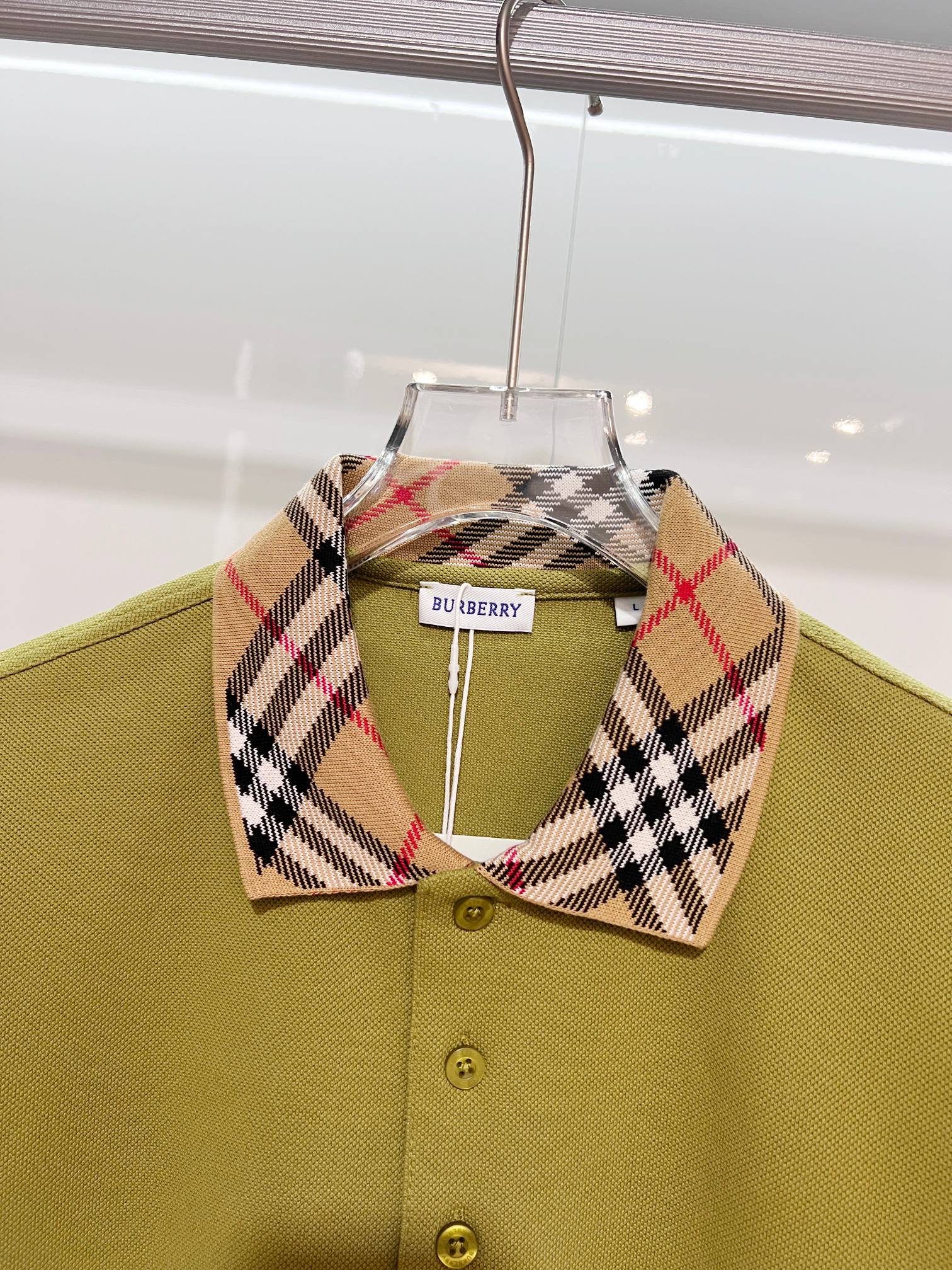 Olive green polo shirt with plaid check collar and button placket, close-up