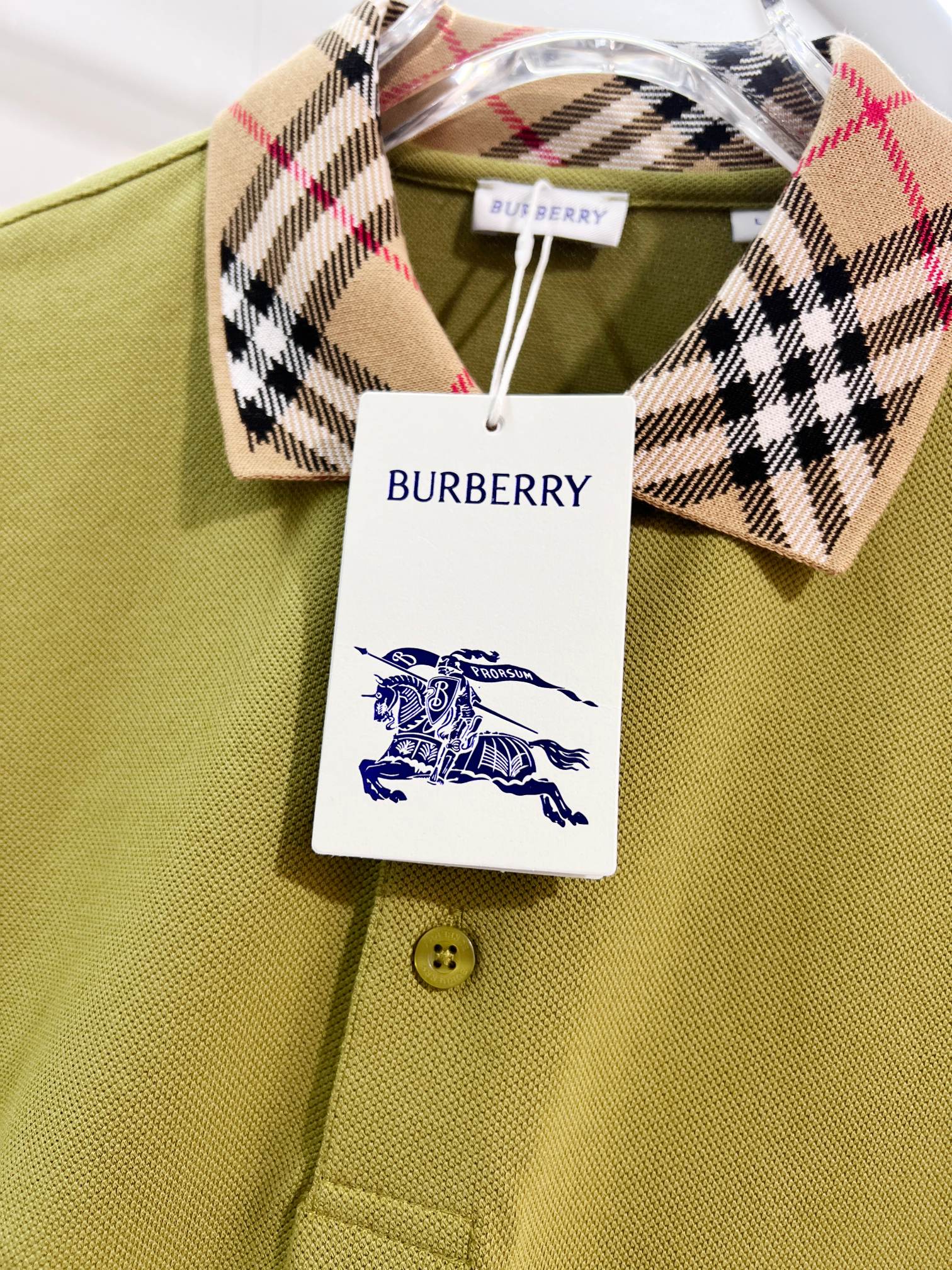 Olive green polo shirt close-up with plaid check collar and round gold buttons