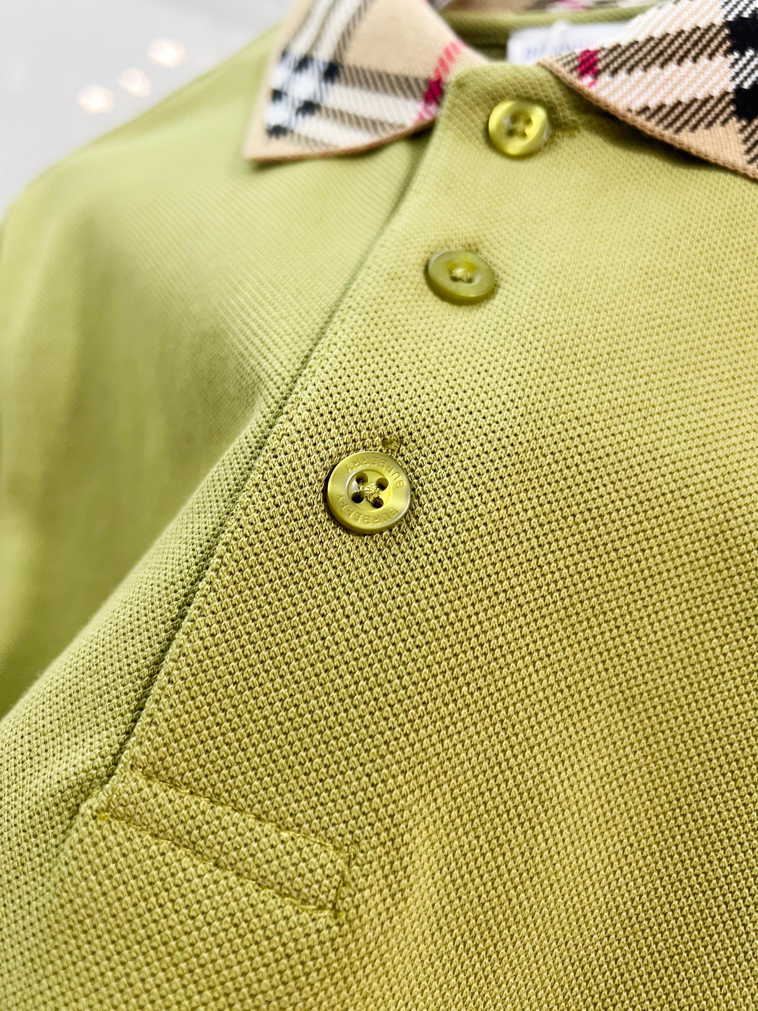 Olive green polo shirt close-up showing textured fabric and round gold buttons