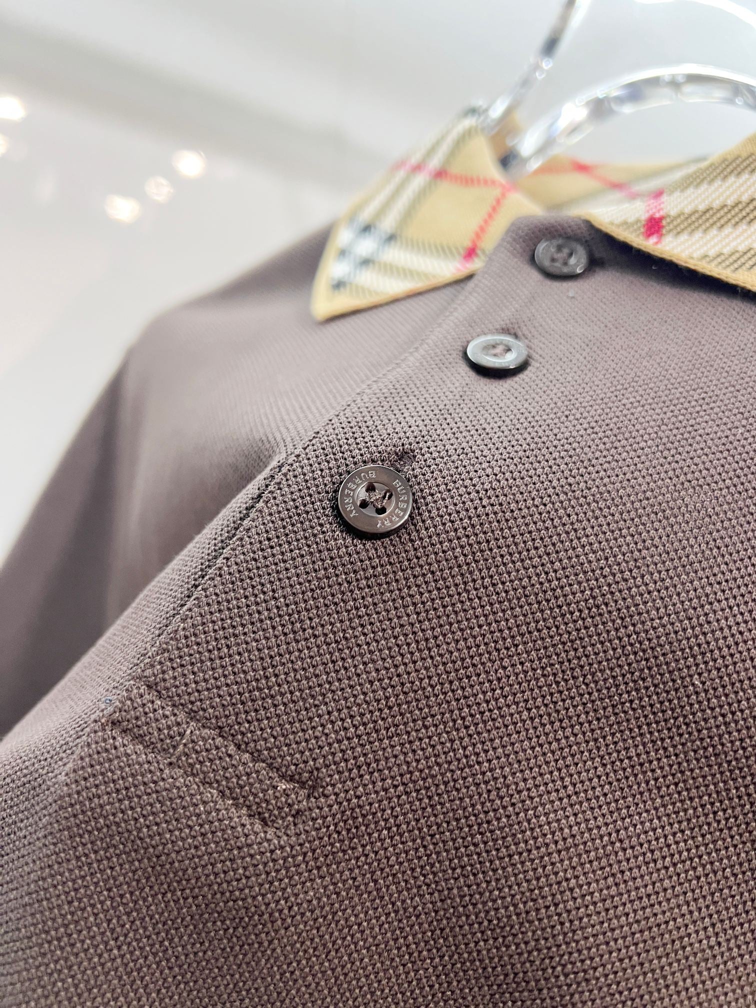Burberry polo shirt close-up, dark brown textured knit with logo buttons