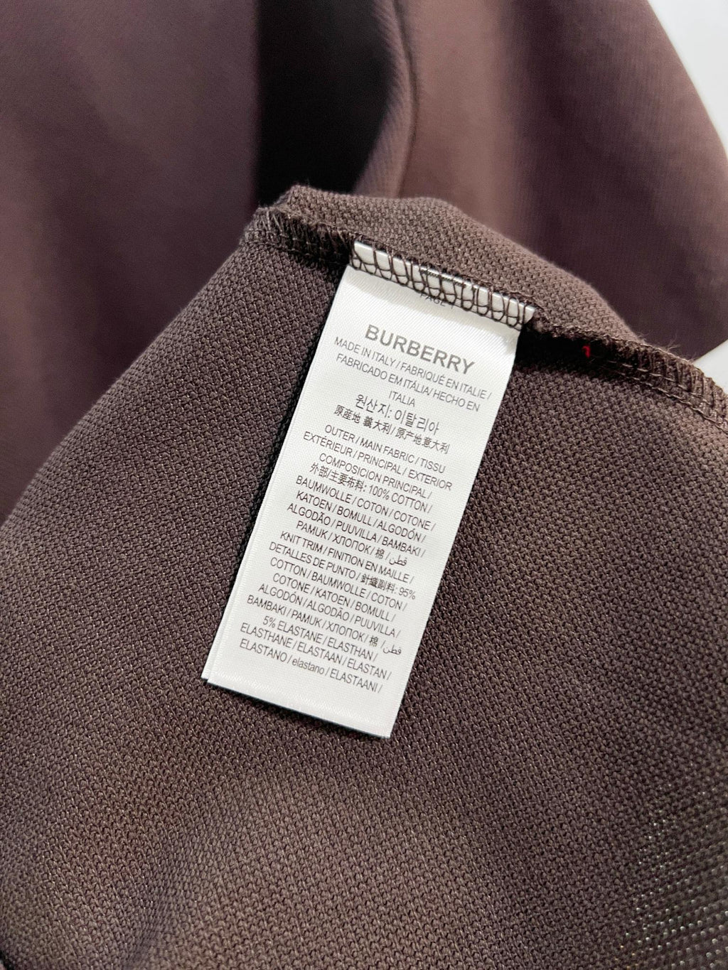 Burberry polo shirt care label on dark brown textured fabric