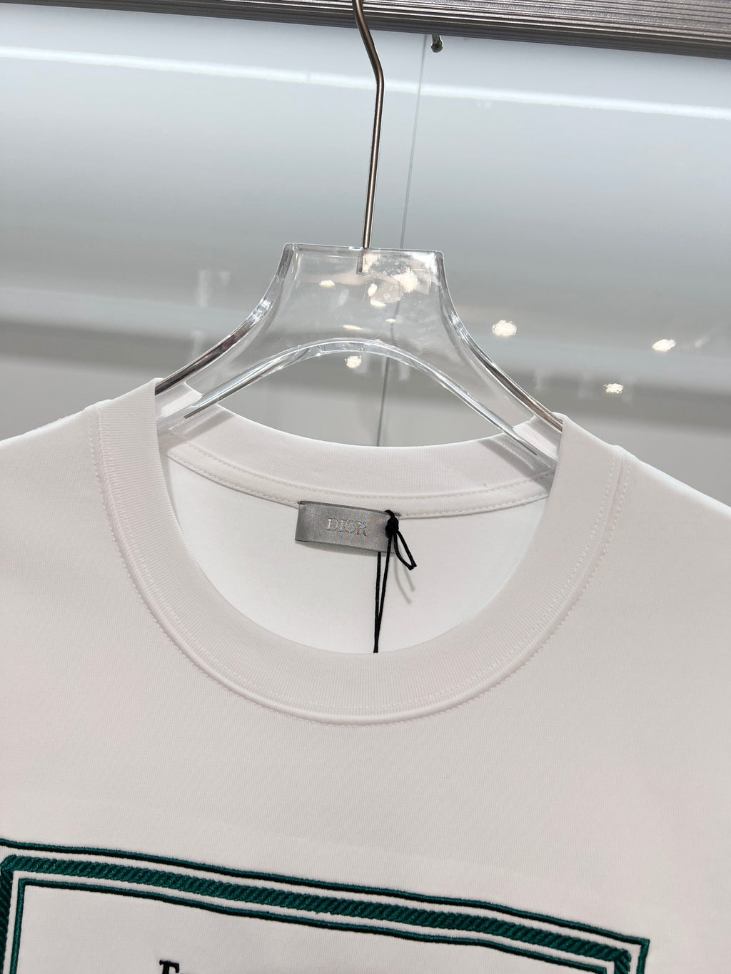 White Dior T-shirt neckline close-up on clear hanger