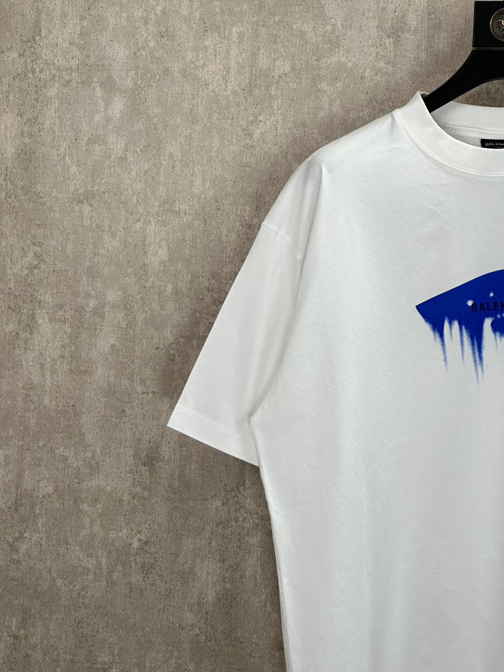 White T-shirt sleeve and shoulder detail with partial blue paint graphic