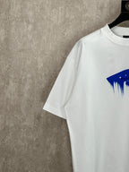 White T-shirt sleeve and shoulder detail with partial blue paint graphic