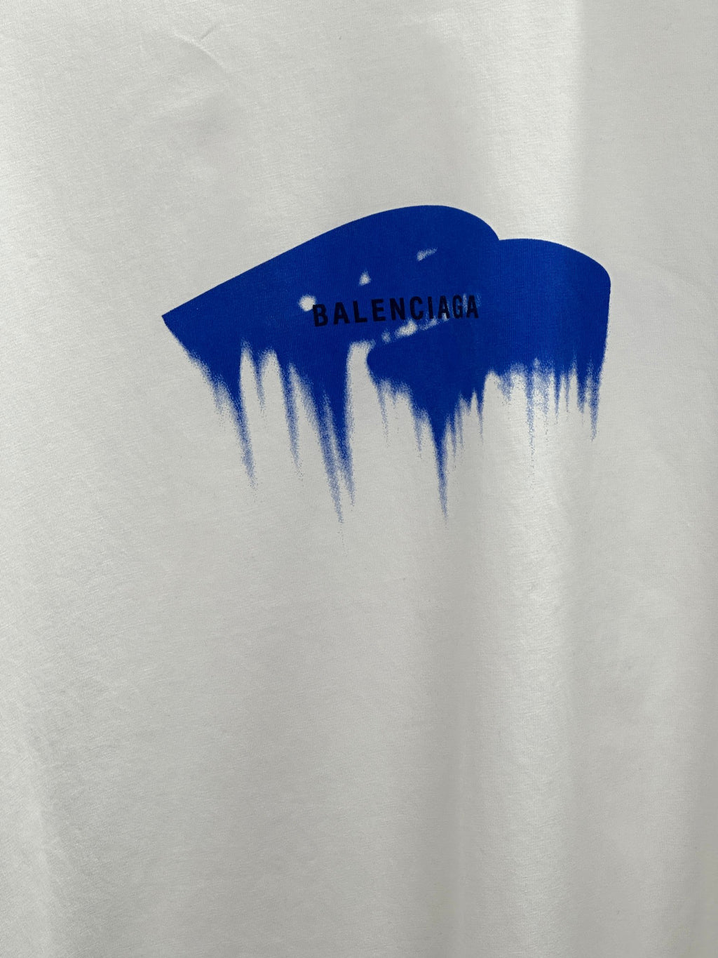 White T-shirt close-up of blue paint graphic with Balenciaga text