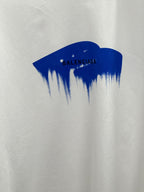 White T-shirt close-up of blue paint graphic with Balenciaga text