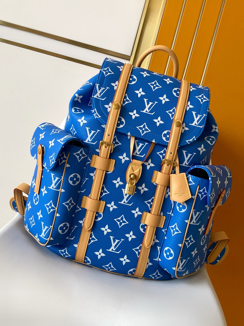 Louis Vuitton blue monogram bag with tan handles and front pocket, side view