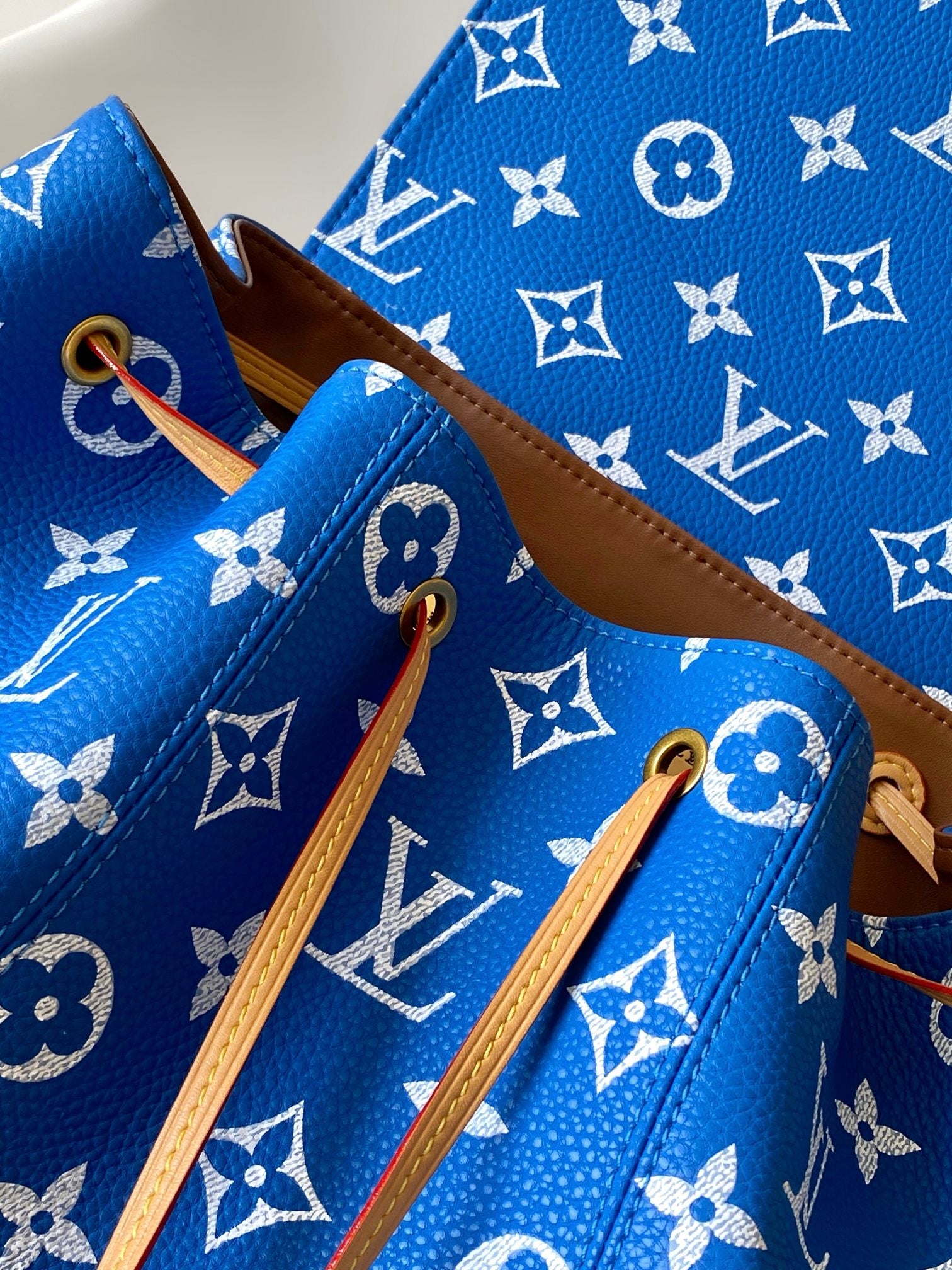 Louis Vuitton blue monogram bag with tan shoulder straps and hanging leather loops