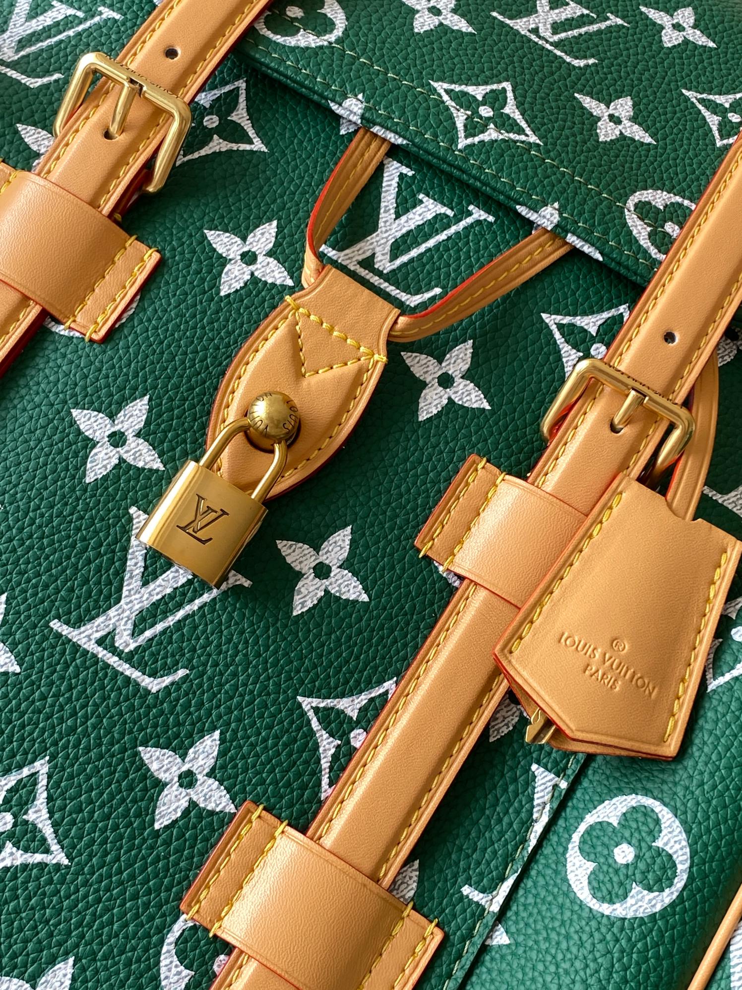 Louis Vuitton green monogram bag with tan straps, buckles, and gold hardware