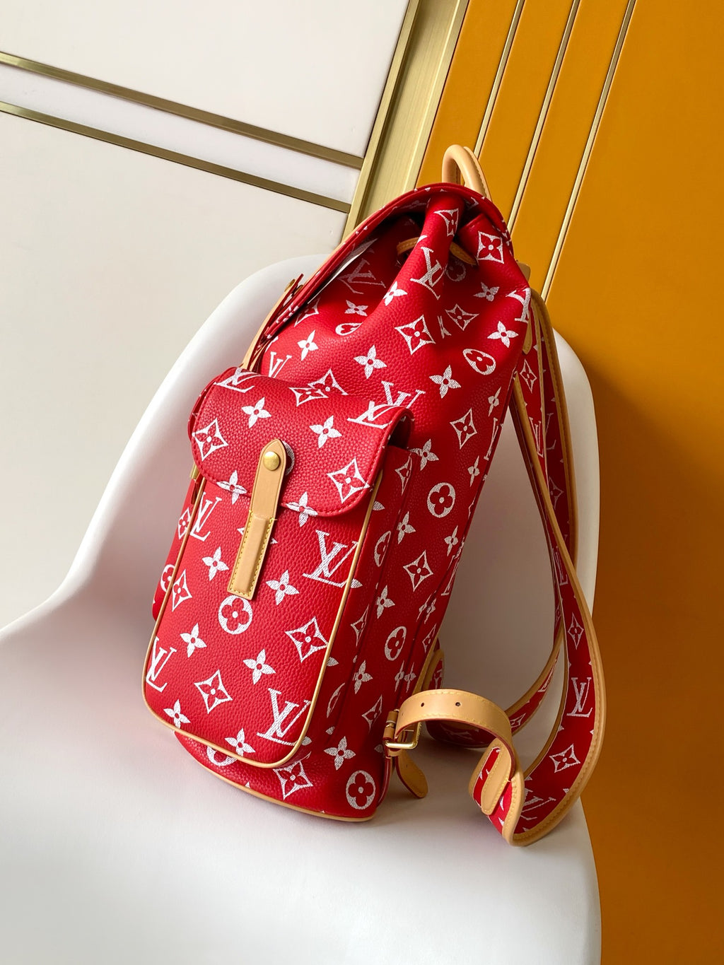 Louis Vuitton red monogram backpack bag with tan leather side strap detail.