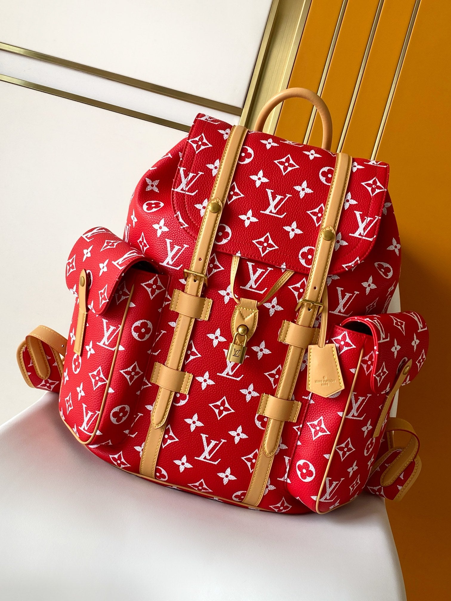 Louis Vuitton red monogram backpack bag with tan leather straps and top handles.