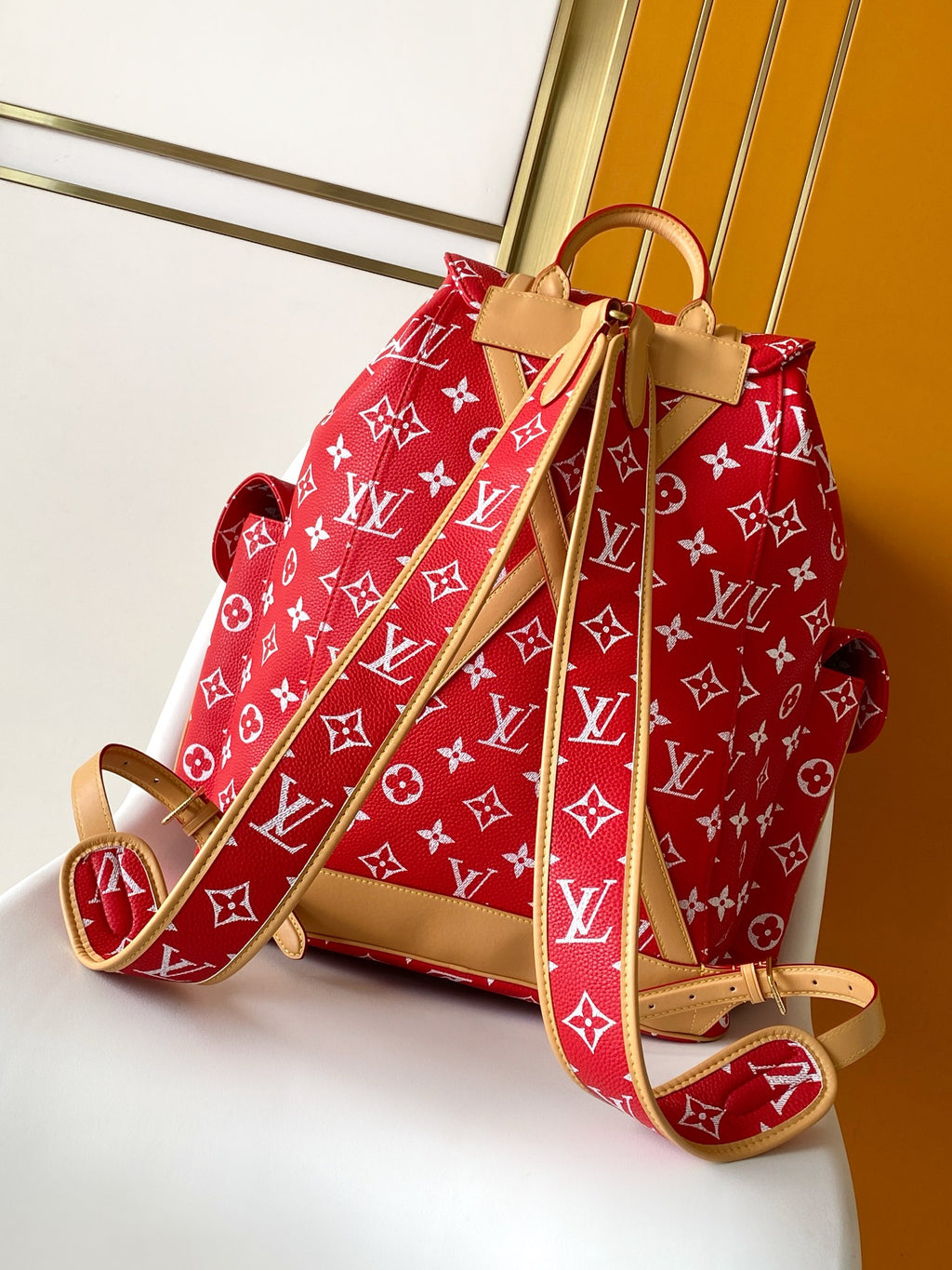 Louis Vuitton red monogram backpack bag with tan leather shoulder straps and handle.