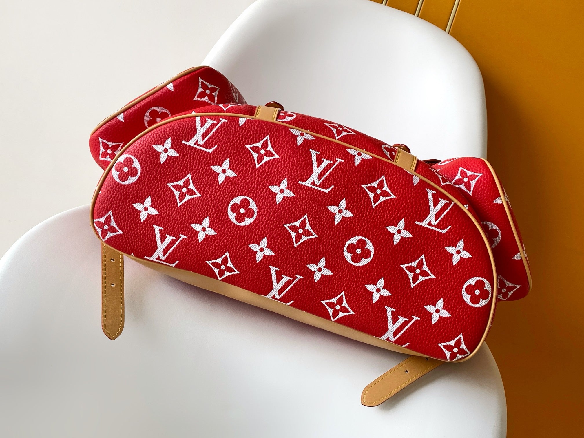 Louis Vuitton red monogram mini bag with tan leather strap and top handle.
