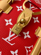 Louis Vuitton red monogram bag close-up with tan leather trim and gold padlock.