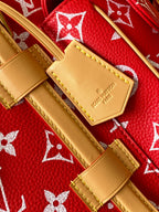 Louis Vuitton red monogram bag close-up with tan leather patch and stitching details.