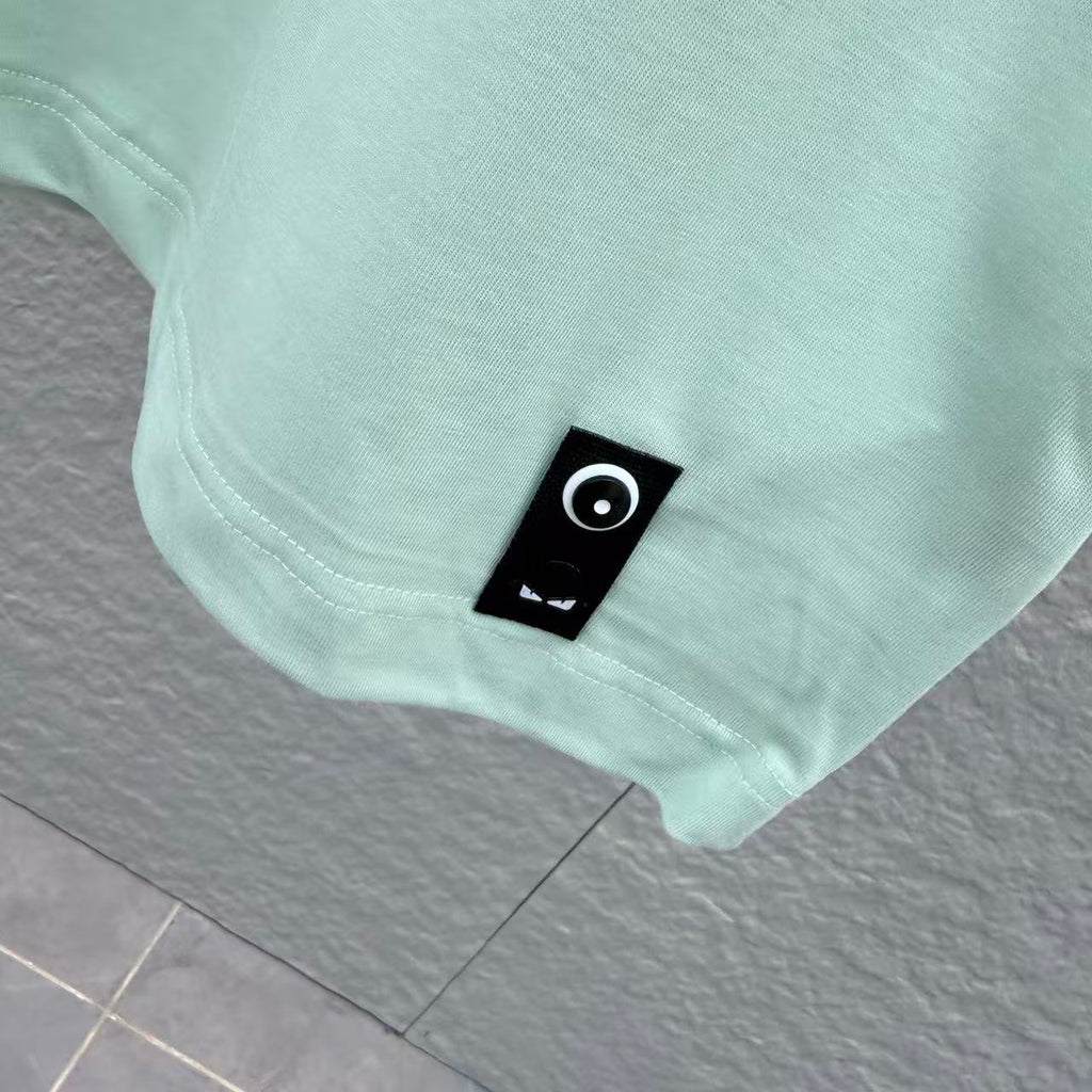 Mint green T-shirt hem with small black brand patch