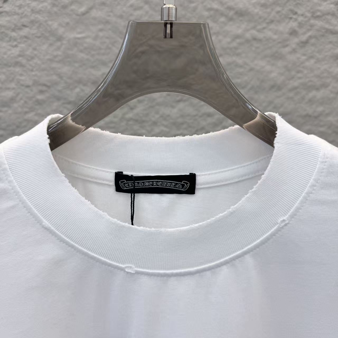 White T-shirt neckline close-up with black brand tag at inner collar