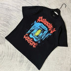 Black T-shirt laid flat with multicolor face graphic and red lettering across chest