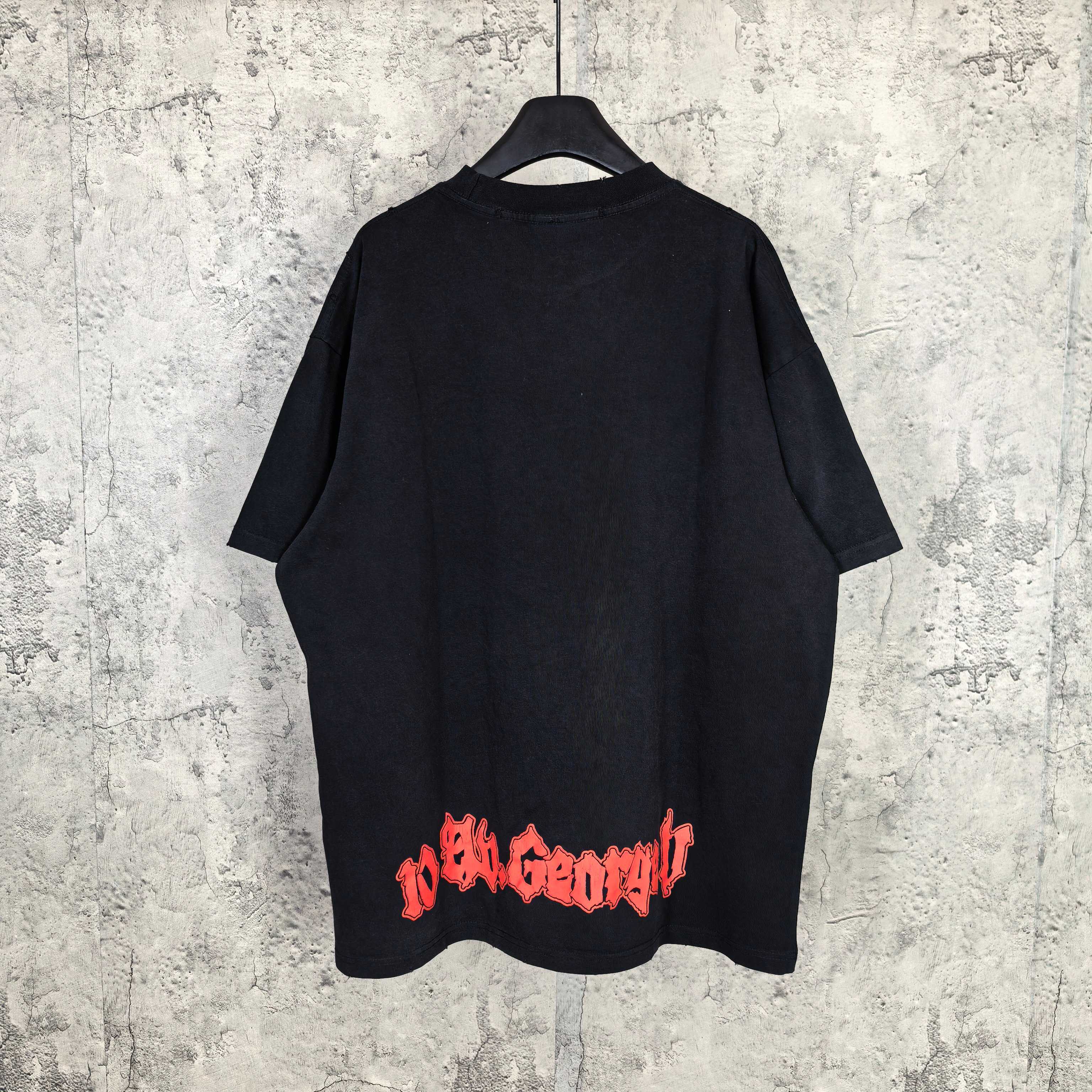 Black graphic T-shirt, back view with red and blue lettering near lower hem