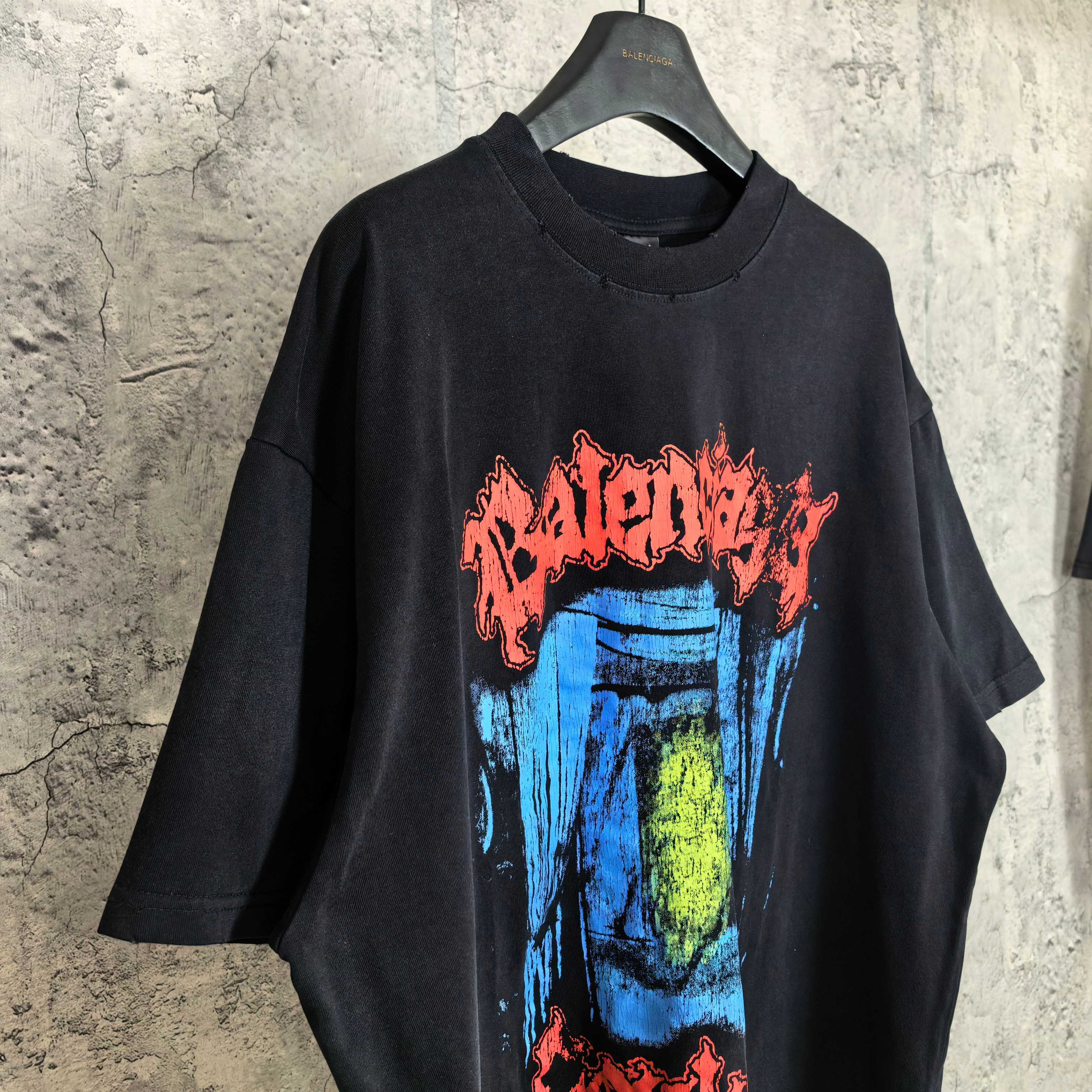 Black graphic T-shirt with blue and yellow face print and red arched text
