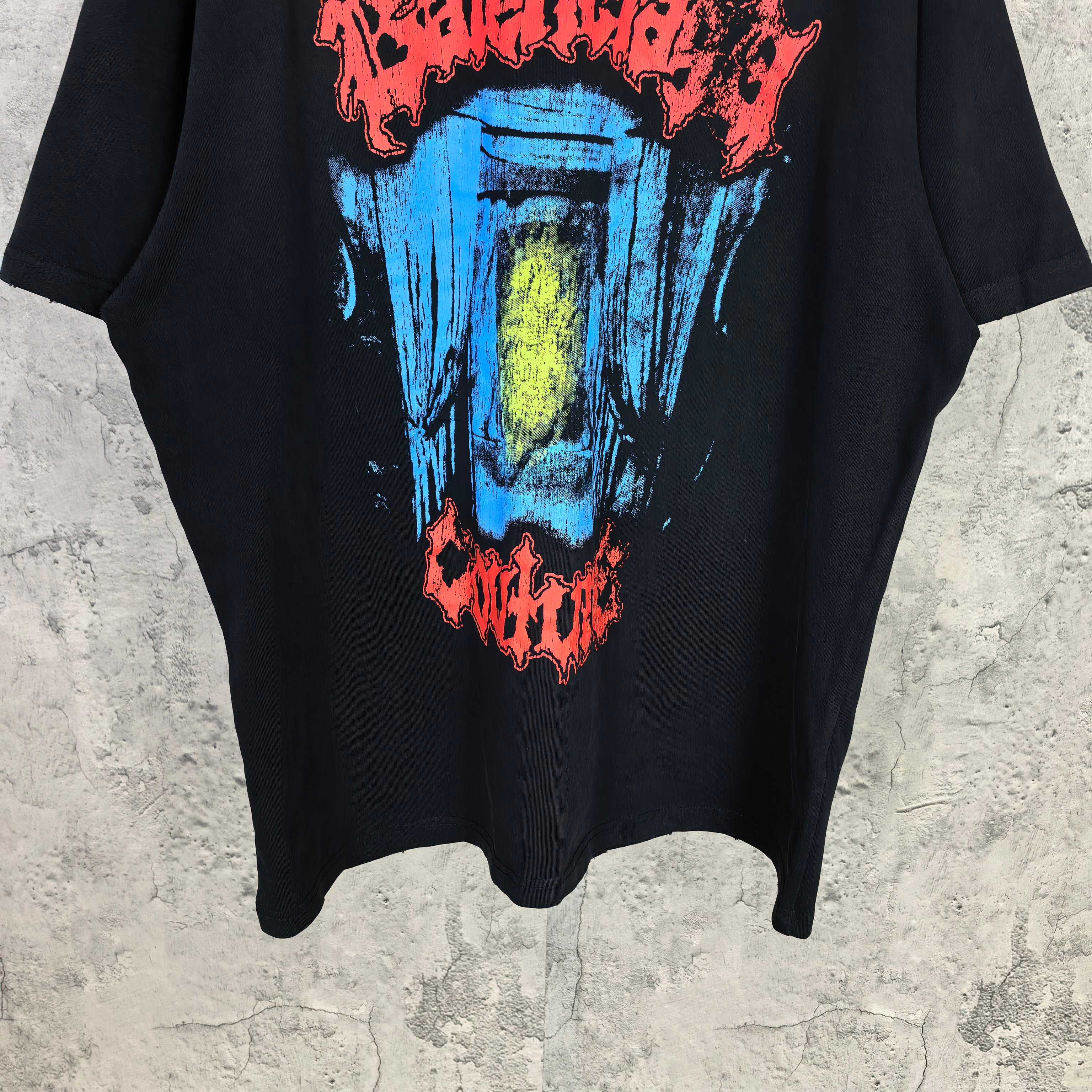 Black graphic T-shirt front hem with multicolor face print and red text