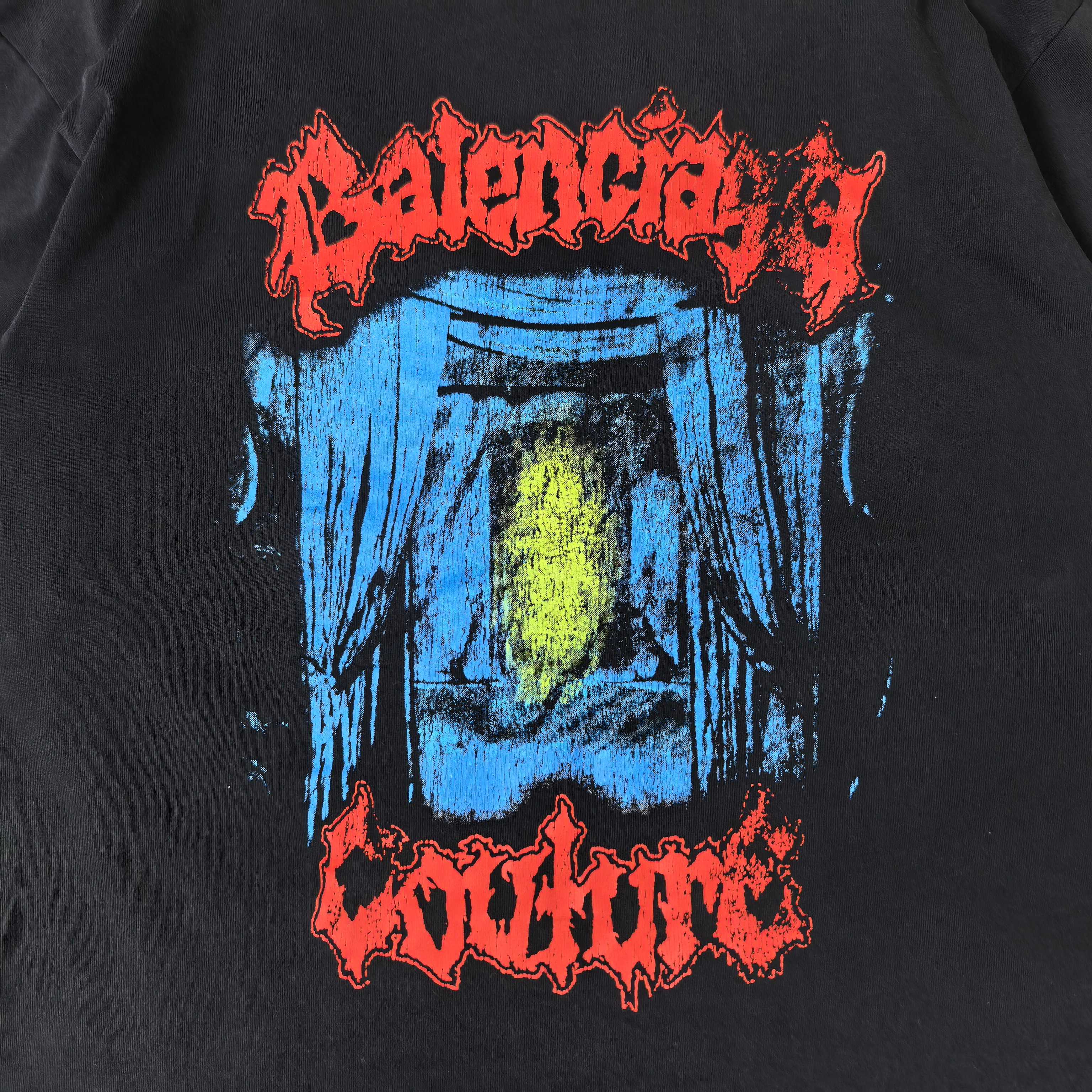 Close-up black T-shirt graphic: red arch text, blue drips, yellow center