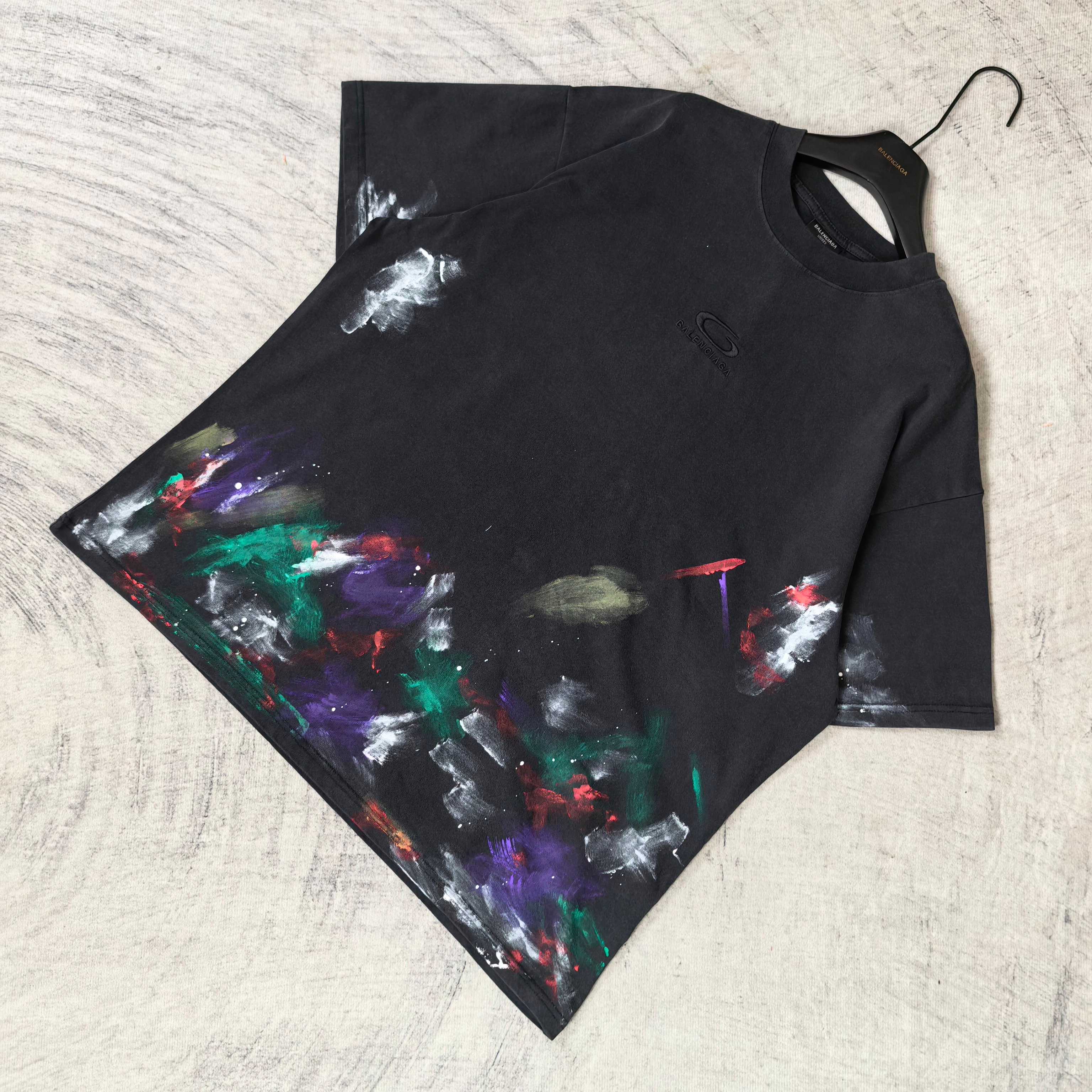 Balenciaga short-sleeve T-shirt laid flat, black with colorful abstract paint print