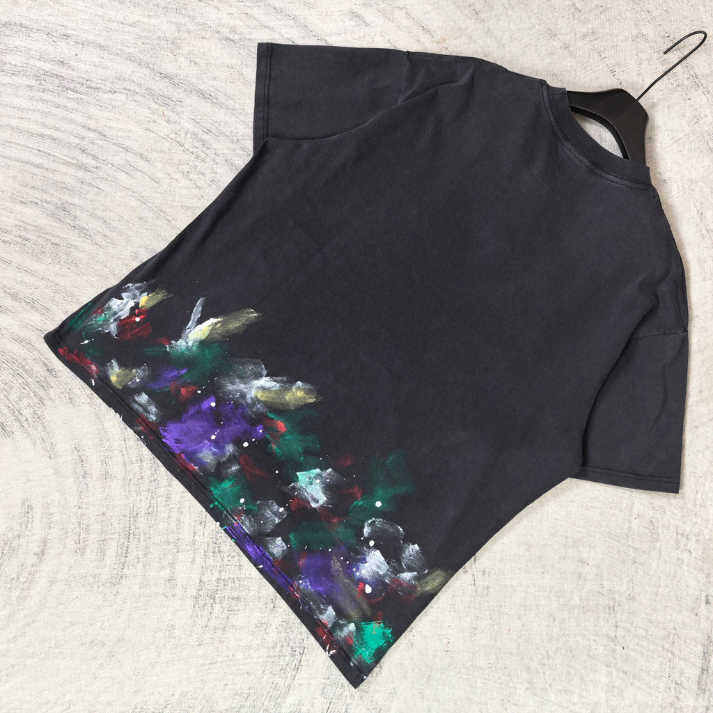 Balenciaga short-sleeve T-shirt laid flat, black with colorful paint print on left side