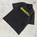 Black short-sleeve T-shirt laid flat with Balenciaga logo graphic on chest.