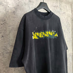 Black short-sleeve T-shirt with Balenciaga logo graphic in yellow and green.