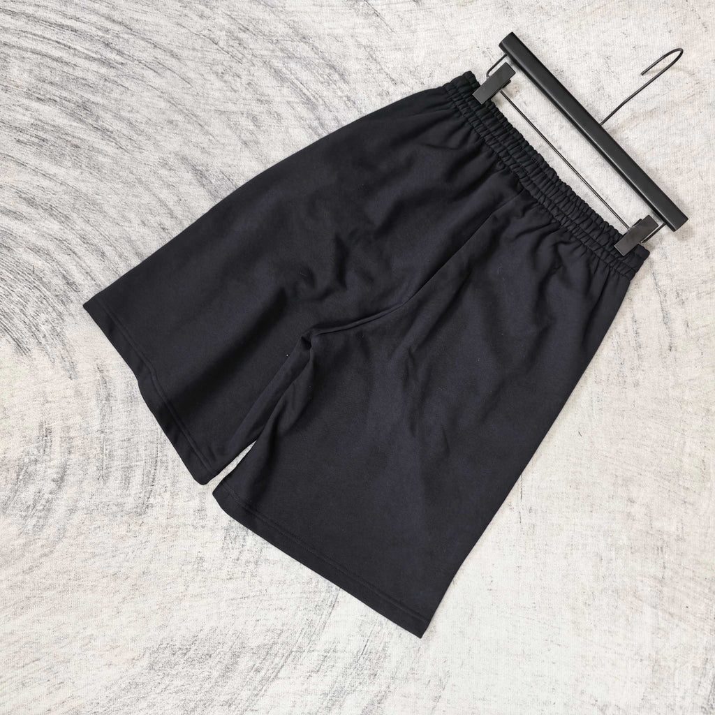 Black shorts with elastic waistband and loose drape, no visible front logos