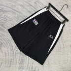 Black shorts with white side stripes, NBA and Balenciaga logos on front, on hanger