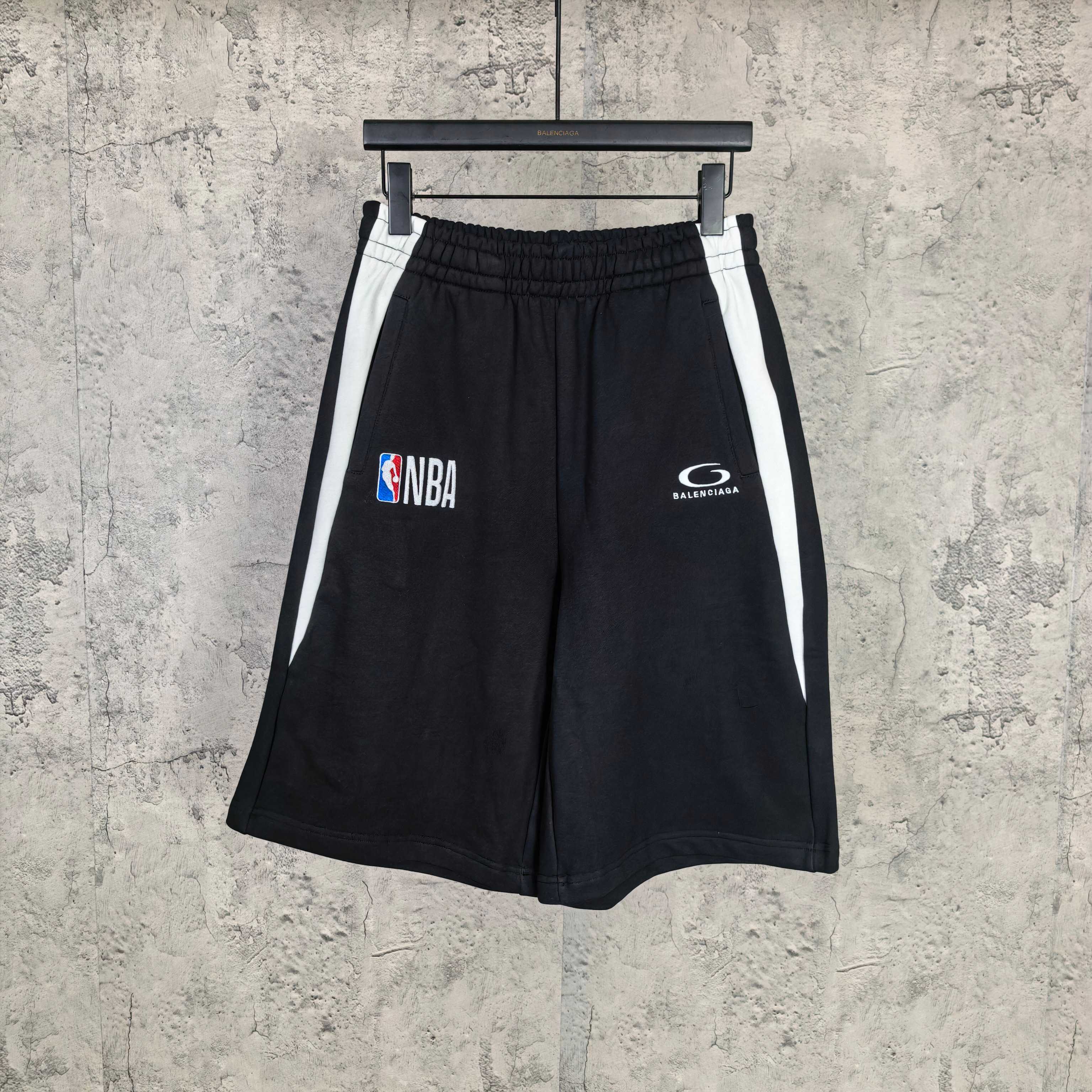 Black shorts with elastic waistband, white side stripes, NBA and Balenciaga logos