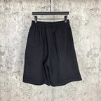 Black shorts with elastic waistband and draped front, plain design