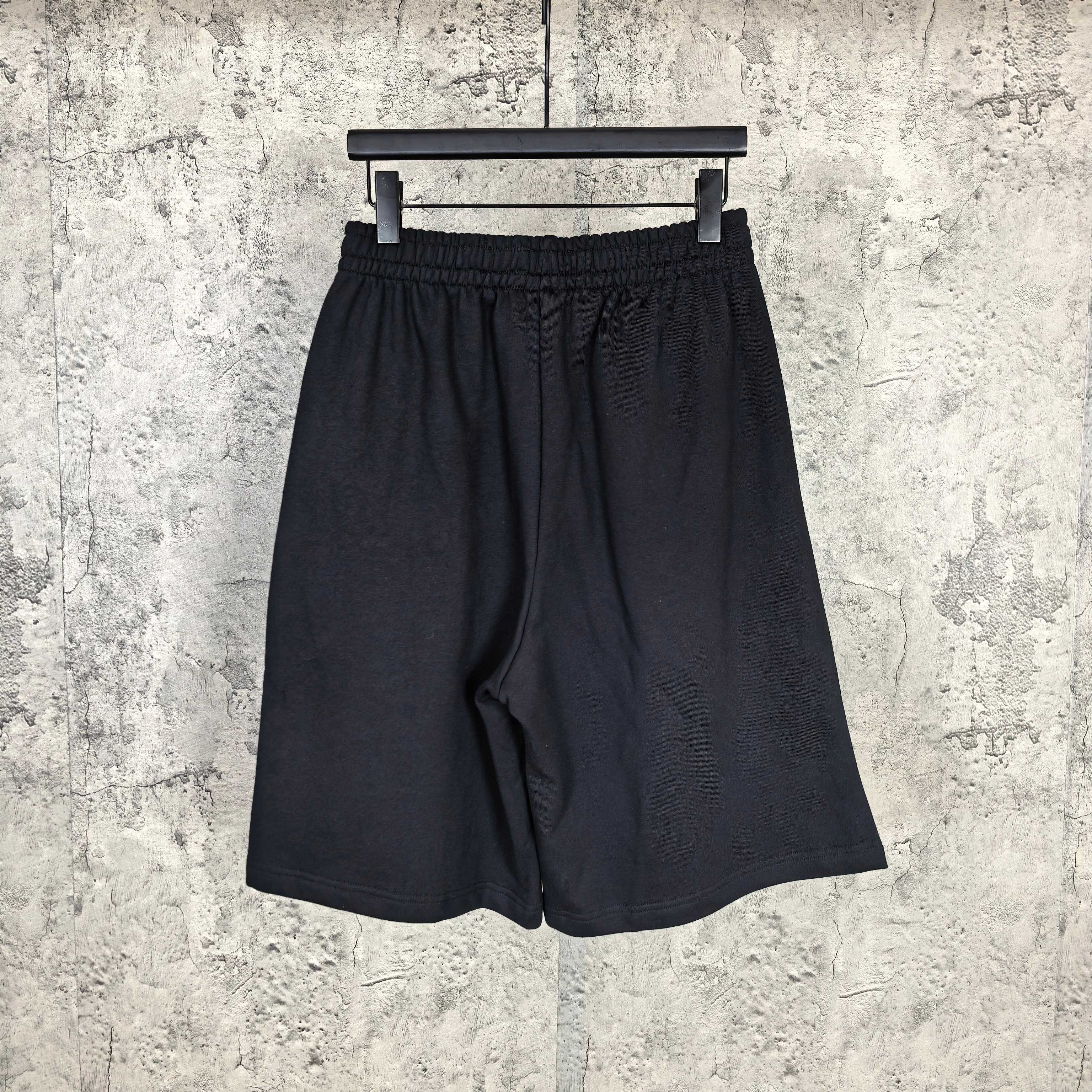 Black shorts with elastic waistband and draped front, plain design