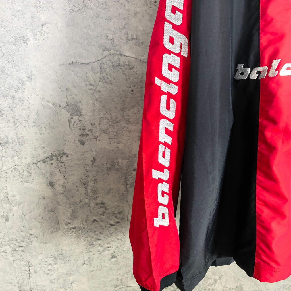 Balenciaga jersey sleeve close-up showing vertical red panel and bold white lettering.