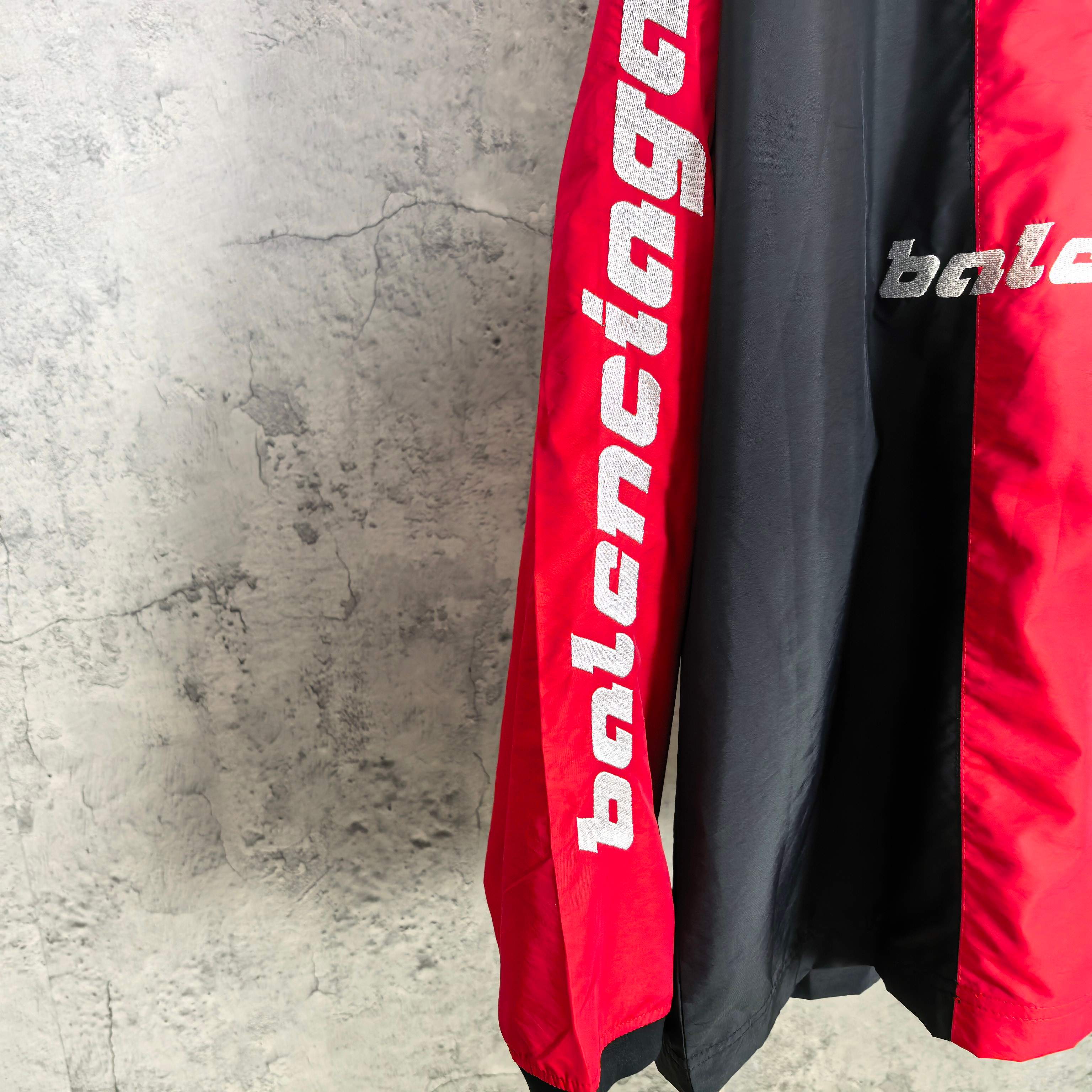 Balenciaga jersey sleeve close-up showing vertical red panel and bold white lettering.