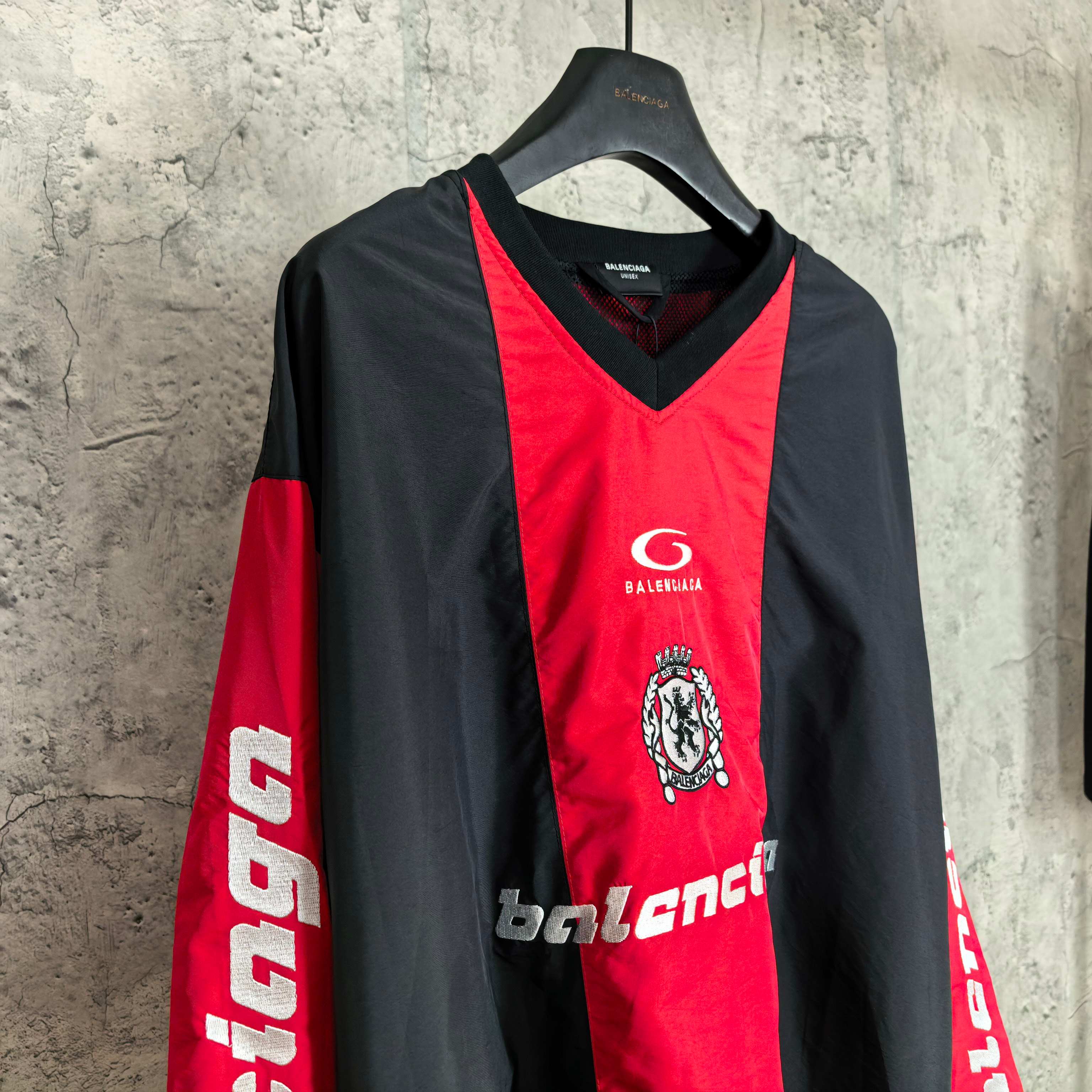 Long-sleeve Balenciaga jersey front with red center, black sleeves, crest and logo details.