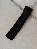 Black fabric brand patch with embossed text on light gray knit
