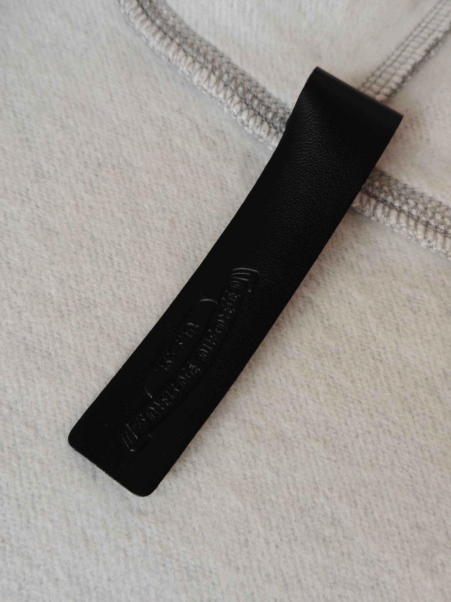 Black fabric brand patch with embossed text on light gray knit