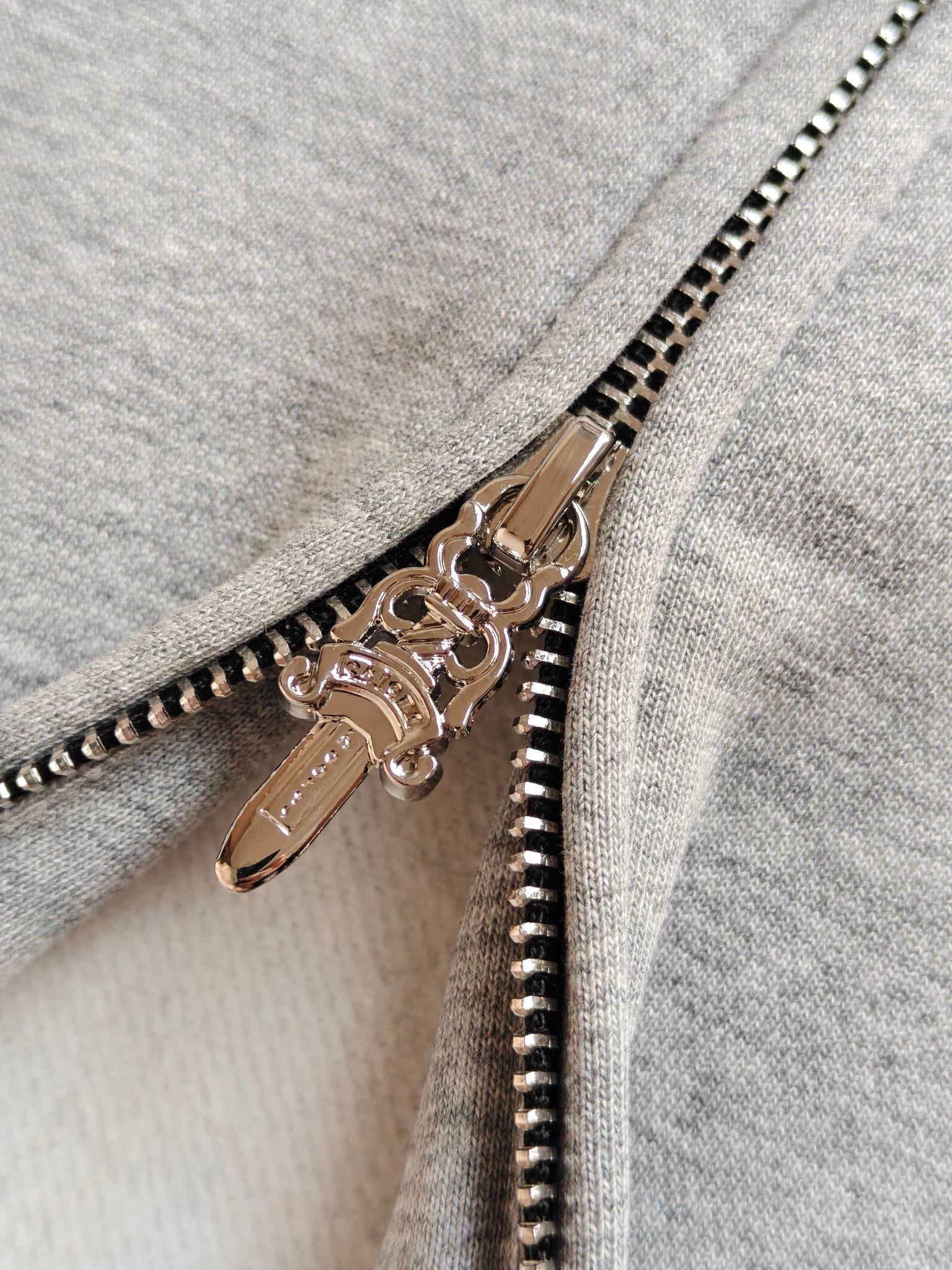 Light gray hoodie zipper with gold-tone metal pull and black beaded trim